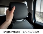 Hand adjusts leather headrest in car interior.