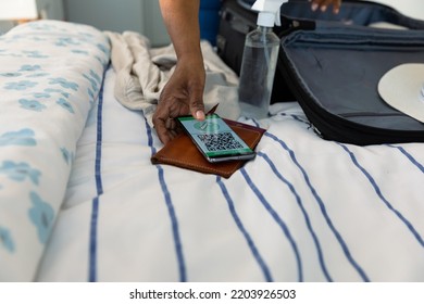 Hand of african american senior woman packing documents and smartphone with covid qr code on screen. travel preparation during covid 19 pandemic. - Powered by Shutterstock