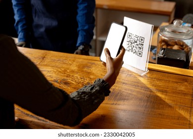 Hand of african american woman scanning qr code using smartphone in cafe. Lifestyle, coffee, communication and local business, unaltered. - Powered by Shutterstock - Get 15% off with code: PIKWIZARD15