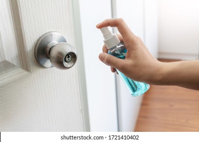 Hand Applying Alcohol Spray And Cleaning To Door, Doorknob Bedroom For Protect Coronavirus, Germs, Virus At The House. Prevention Covid-19 Pandemic.