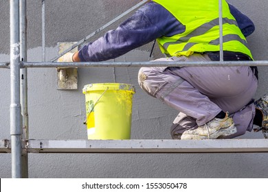 Hand Applying Decorative Plaster On Wall By A Steel Trowel. White Cement Based Decorative Top Coat Plaster Resistant On Outside Whether Conditions. Selective Focus.