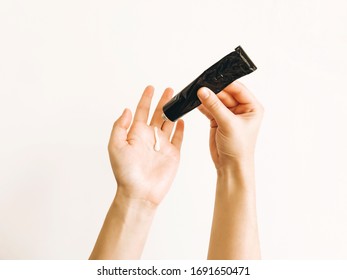 Hand applying moisturizing cream on palm from black tube after washing hands and using alcohol gel during virus epidemic. Treatment for dry skin. Luxury skin care. Hand cream. Avoiding dry skin - Shutterstock ID 1691650471