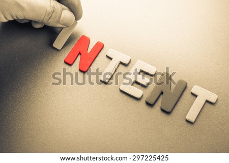 Hand arrange wood letters as Intent word
