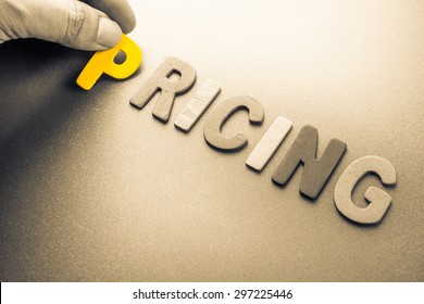 Hand arrange wood letters as Pricing word