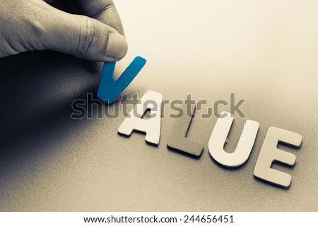 Hand arrange wood letters as Value word
