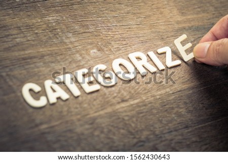 Hand arrange wooden alphabets as Categorize word on wood background