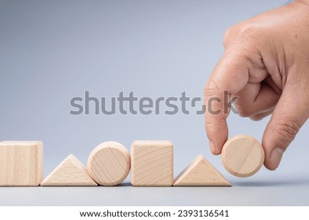 Hand arranges the wooden geometric shape into the same sequence of patterns, logic game, test, and learning