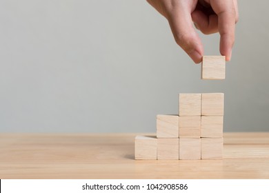 Hand arranging wood block stacking as step stair on wooden table. Business concept for growth success process. Copy space