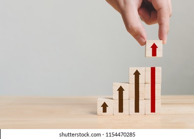 Hand arranging wood block stacking as step stair with arrow up. Ladder career path concept for business growth success process