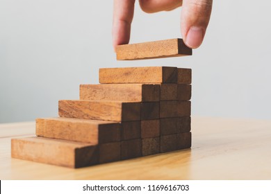 Hand arranging wood block stacking as step stair. Ladder career path concept for business growth success process - Shutterstock ID 1169616703