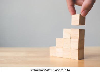 Hand Arranging Wood Block Stacking On Top With Wooden Table. Business Concept For Growth Success Process