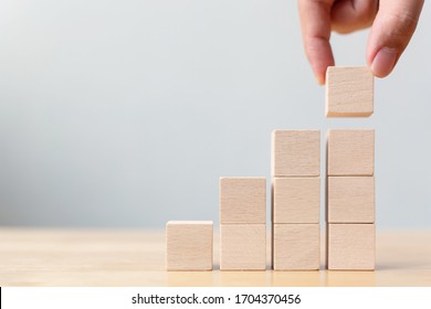Hand arranging wood block stacking as step stair on wooden table. Business concept for growth success process. Copy space