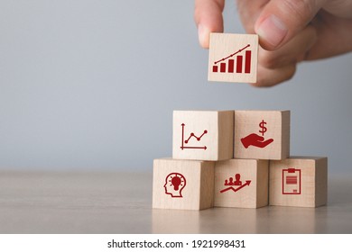 Hand arranging wood block stacking with icon arrow and business,targeting the business concept. - Shutterstock ID 1921998431
