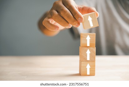 Hand arranging wood block stacking step stair with an upward arrow. Ladder career path for business growth and success process concept. Build your way up for increased revenue and personal development