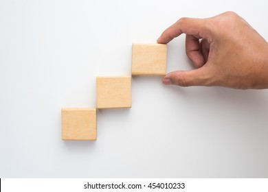 Hand arranging wood block stacking as step stair. Business concept for growth success process.
