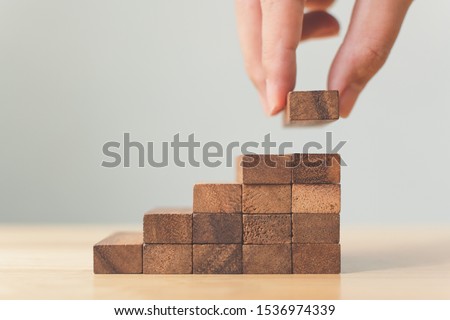 Hand arranging wood block stacking as step stair. Ladder career path concept for business growth success process, Copy space