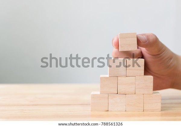 Hand arranging wood block stacking\
as step stair. Business concept for growth success\
process