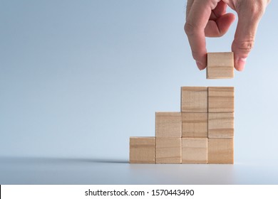 hand arranging wood cube stacking as stair step shape, mock up for create symbol or logo, business growth and management concept
