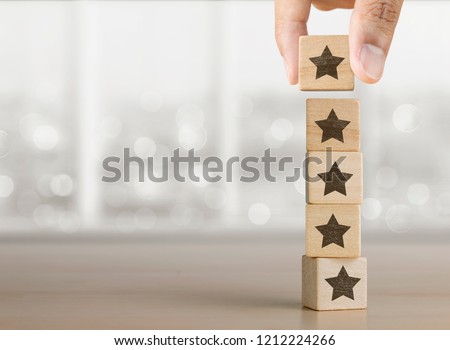 Hand arranging wooden blocks with the five star symbol. The best rating, the best ranking, the best service, goal, success concept.
