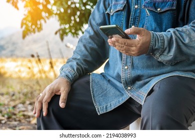 Hand of Asian elderly man farmer use cellphone for business to plan farming in meadow. Male farmers consult with landowners to cultivate crops in field. Farm and agricultural technology and business. - Powered by Shutterstock