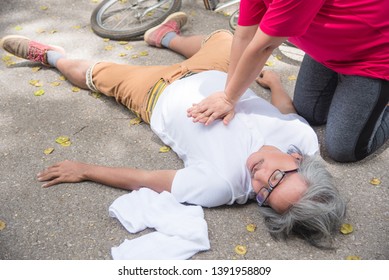 Hand of Asian Woman First Aid Emergency CPR on Heart Attack Senior senior man with cardiac arrest while exercise in park. Basic life support concept .