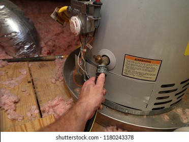 Рука прикрепляет шланг к домашнему водонагревателю для выполнения технического обслуживания