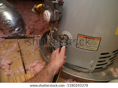 Hand attaches hose to a home water heater to perform maintenance
