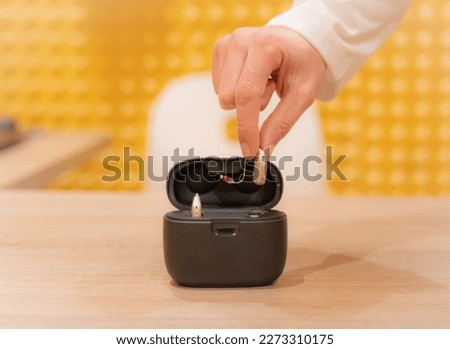 Hand of an audiologist doctor placing a hearing aid in its cas