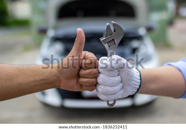 hand of an auto\
mechanic holding a wrench and the hands of a customer who visits\
the service, appreciates the service and care of the customer,\
making the customer\
satisfied.