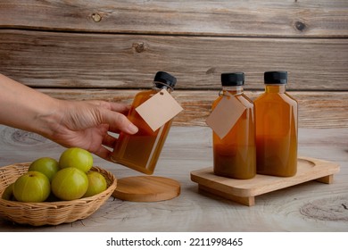 Hand And Ayurvedic Amla Or Indian Gooseberry Juice, Healthy Diet On Wood Table