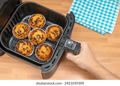 HAND BAKING HOMEMADE MUFFINS OR CUPCAKES WITH CHOCOLATE CHIPS IN AIR FRYER AT THE KITCHEN. TOP VIEW. - Powered by Shutterstock