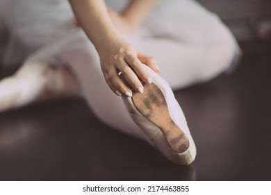 Hand Of A Ballerina Touching Pointe Shoes On A Floor. Little Girl Warming Up Stretching And Practicing In Ballet Dance Class. Young Teen Before Dancing. Classical Art Dancers Practice Professional.