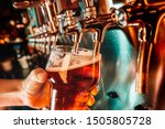 Hand of bartender pouring a large lager beer in tap. Bright and modern neon light, males hands. Pouring beer for client. Side view of young bartender pouring beer while standing at the bar counter.