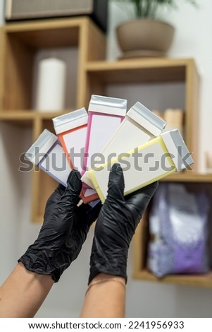 hand of a beautician holding fat-soluble wax cartridges for hair removal. wooden spatulas for wax. Preparation for epilation.