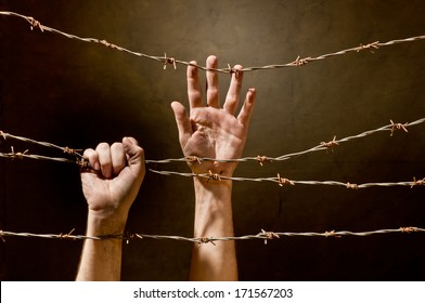 hand behind barbed wire