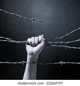 hand behind barbed wire with dark background - Shutterstock ID 222669757