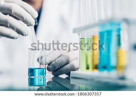 Hand of Biochemical research scientist working with science laboratory test tubes for coronavirus vaccine development in pharmaceutical research labolatory.