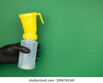 Hand In Black Nitrile Glove Holds A Teat Dip Cup For Udder Cow Disinfection On The Green Background, Copy Space. Milking Procedure