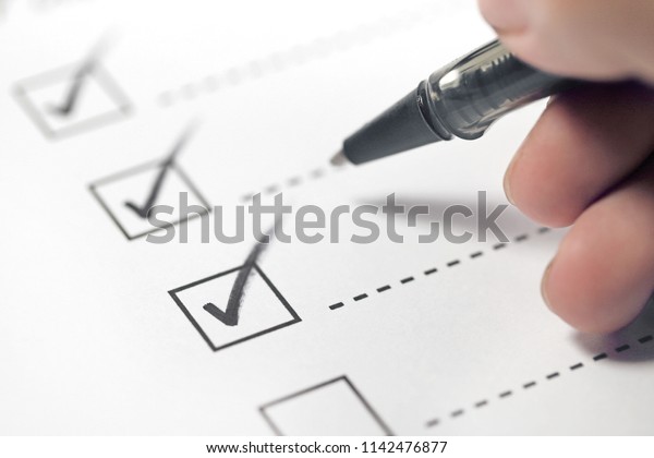 Hand with black\
pen marking on checklist\
box.