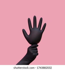 A Hand In A Black Surgical Glove Holds The Inflated Glove Like A Balloon. Pink Background. Pop Art Style. Symbol Of Celebration Of The Victory Over The Coronavirus Pandemic.