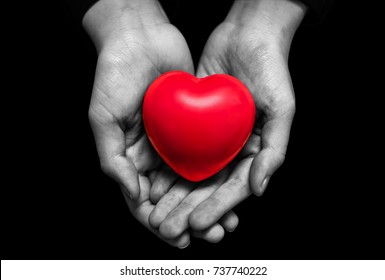 hand in black and white tone holding red heart isolated on black background