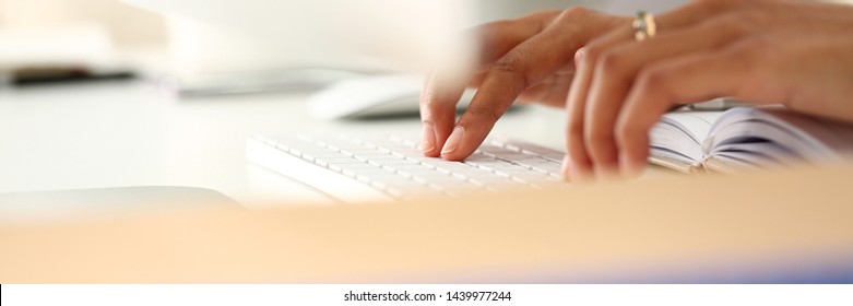 Hand of black woman type something with white wireless computer keyboard closeup