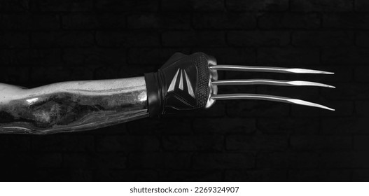 hand with blade claw weapon on black background