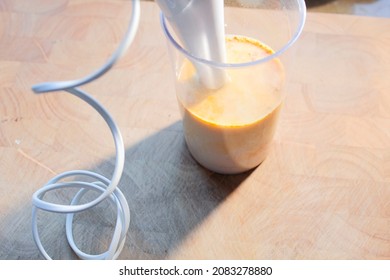 A Hand Blender That Stands In A Mug. In The Form Is Oat Milk And Banana For Making A Banana Shake.