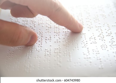 Hand of a blind person reading some braille text touching the relief. Empty copy space for Editor's content.