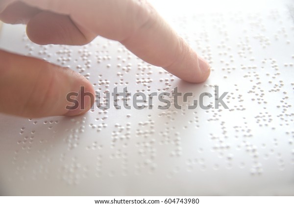 Hand of a blind\
person reading some braille text touching the relief. Empty copy\
space for Editor\'s\
content.