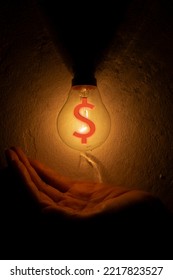 A Hand Blocking Light From A Light Bulb With A Dollar Sign. Business Money Protection Concept.