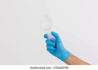 Hand In Blue Disposable Medical Glove Holds Nebulizer Drug Reservoir With Silicone Mask, Inhalation Device, Pulmonology Concept, Blue Background, Copy Space