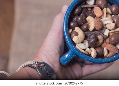 A Hand With A Blue Enamelware Cup Of Trail Mix.