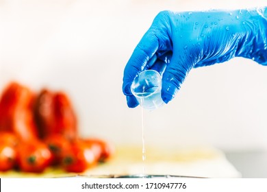 Hand with blue latex gloves pouring disinfectant liquid to decontaminate fruit and vegetables from viruses. Washing the fruit with bleach.